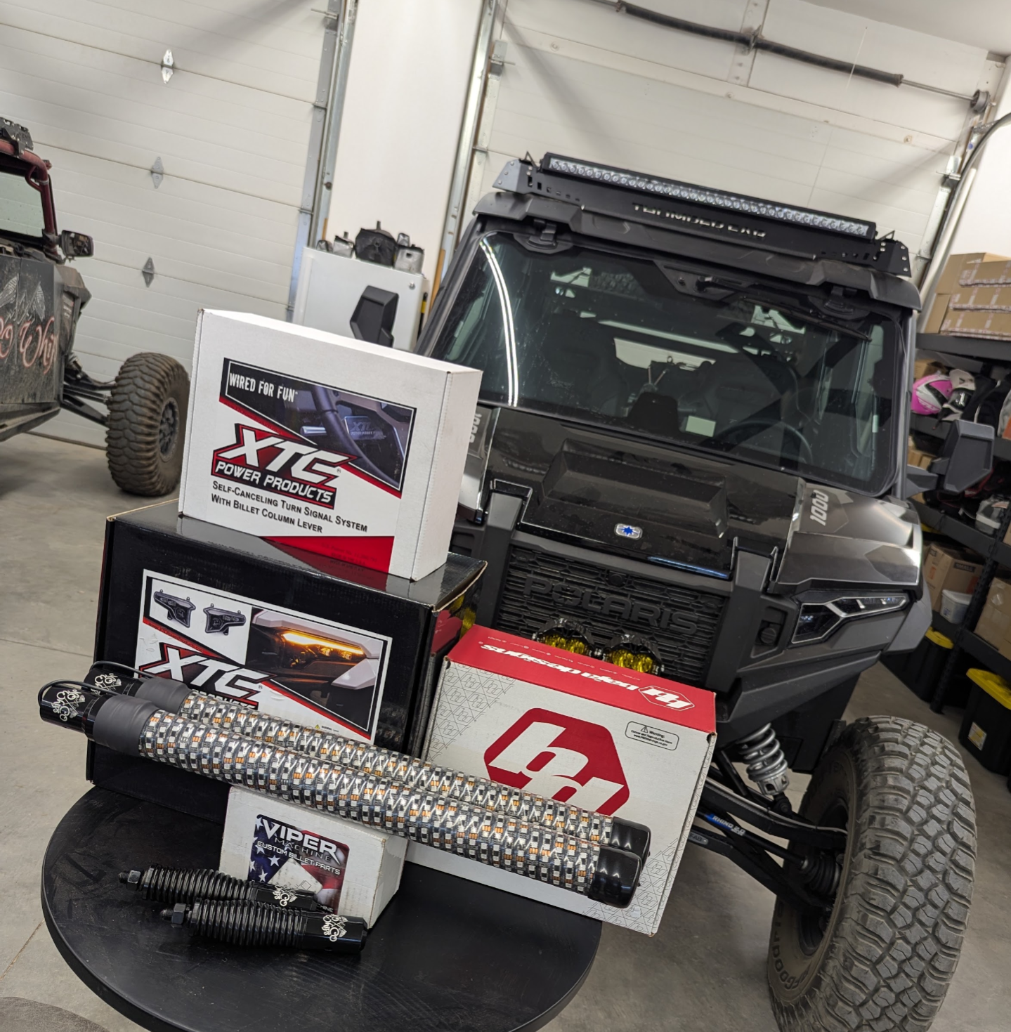 LED whips and UTV accessory parts displayed in front of a Polaris in the NoCo Whips shop